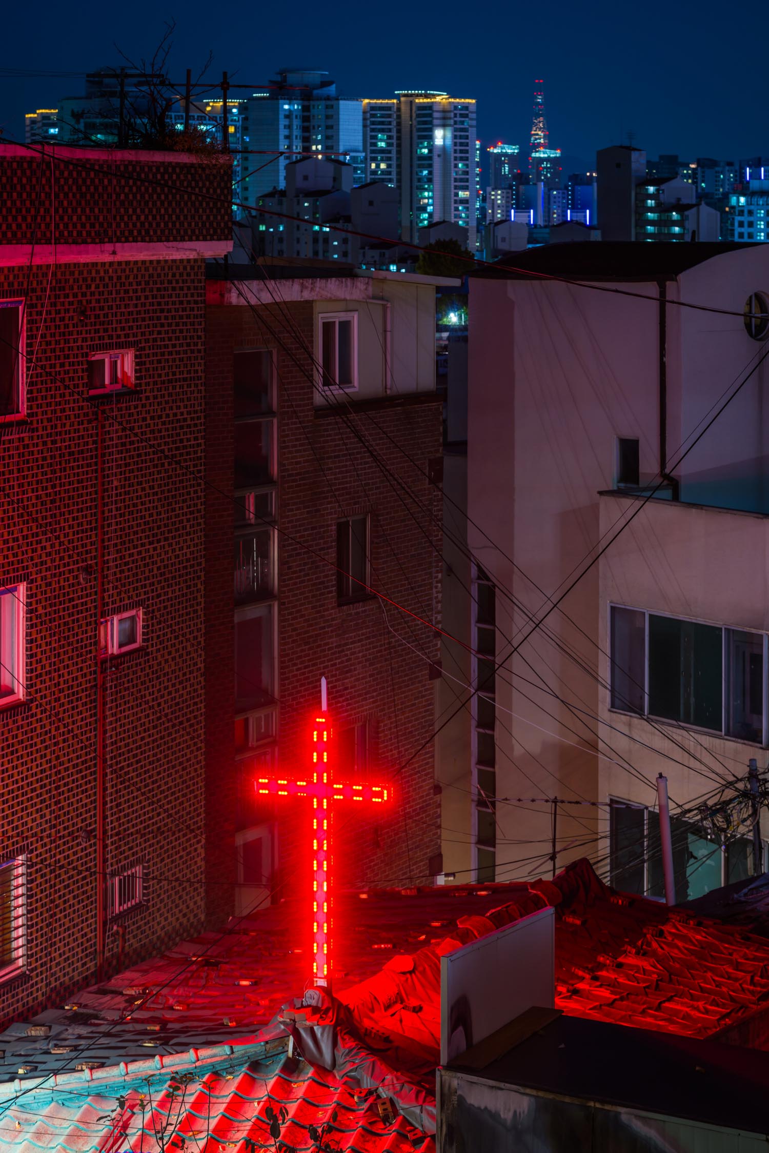 Seoul neon cross illuminated in quiet city night between skyscrapers Korea