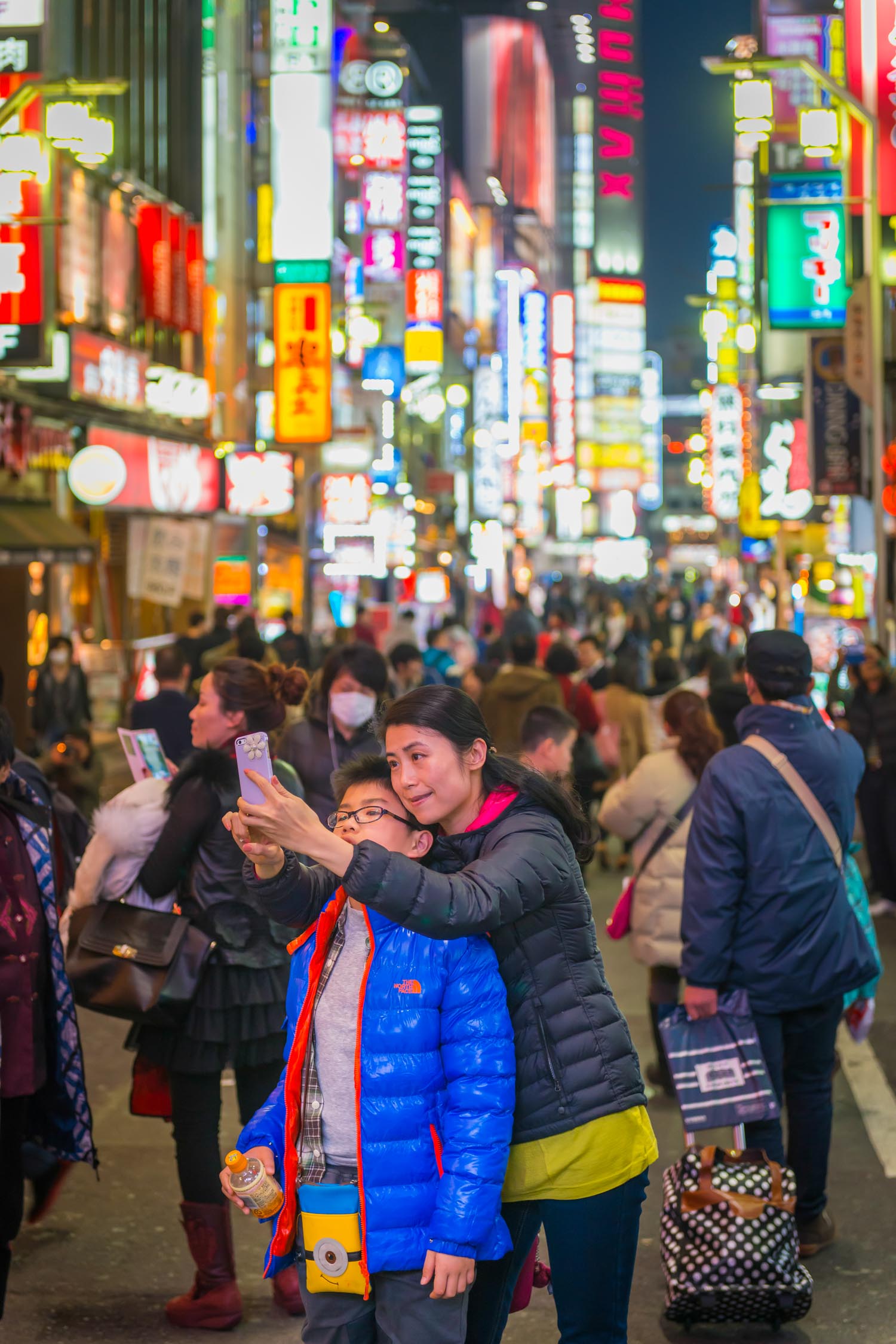 Tokyo woman child photographing selfie crowded neon night city Japan
