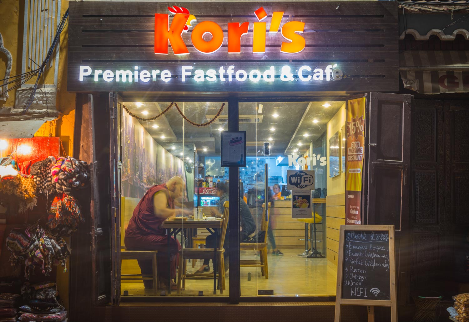 buddhist monk in fast food cafe illuminated at night Kathmandu